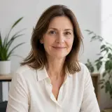 Portrait de Dorothée Laprade, cheveux bruns mi-longs, chemisier clair, léger sourire, fond de bureau lumineux et flou