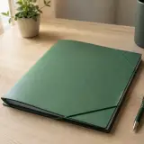 Un dossier à élastique vert posé sur un bureau, un stylo à côté