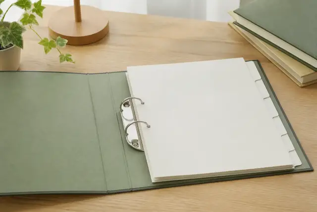 Un classeur d’archives ouvert avec des intercalaires pâles vierges, posé sur un bureau en bois clair