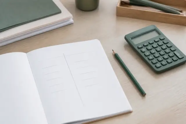 Carnet ouvert avec un tableau à deux colonnes, seuils de chiffre d’affaires barrés au crayon, une calculatrice à côté