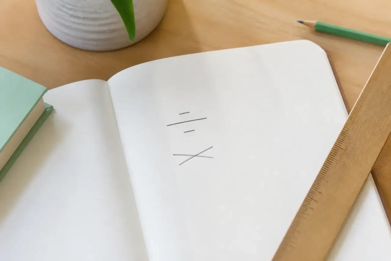 Page de carnet avec une fraction manuscrite, un prix toutes taxes comprises barré d’un trait de crayon, une règle plate
