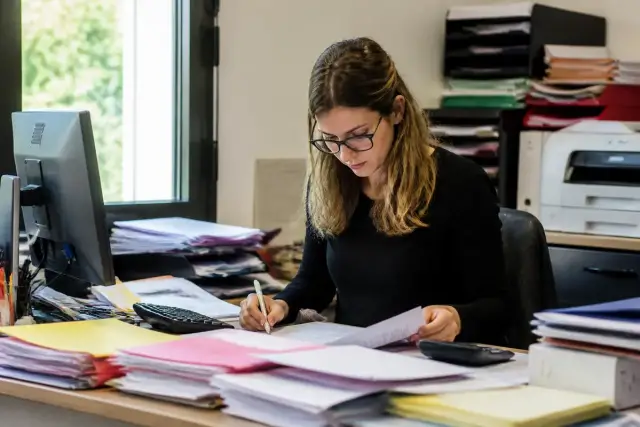 Femme travaillant sur des documents administratifs, tva non applicable selon l'article 293B du CGI