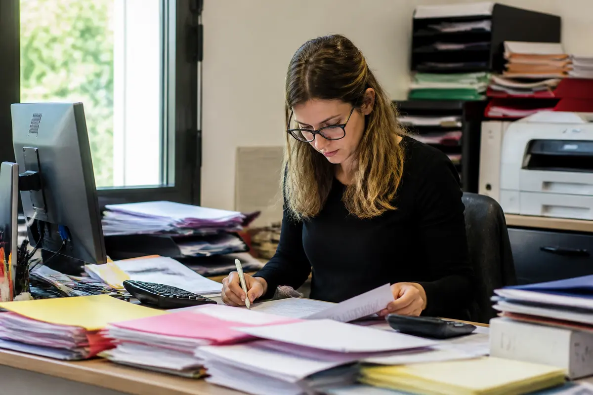 Femme travaillant sur des documents administratifs, tva non applicable selon l'article 293B du CGI