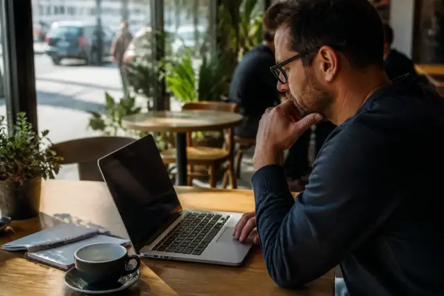 Homme travaillant sur ordinateur portable dans un café, lié à l'Urssaf pour autoentrepreneur